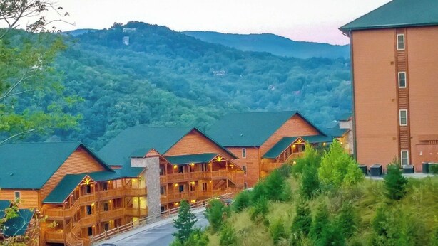 Eine Lodge mit mehreren Holzhäusern, einer Straße davor und einer bergigen Kulisse.