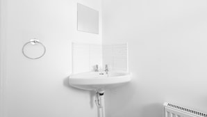 Ein helles Badezimmer mit einem Standwaschbecken, einem Handtuchhalter, einem Spiegel und einer Heizung.