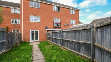 A brick apartment with a wooden fence, a pathway, and a door leading to a garage.