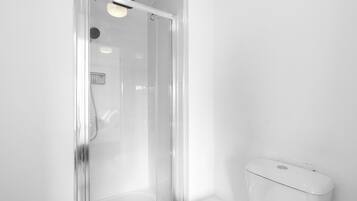 Un baño moderno con cabina de ducha de vidrio, inodoro y ducha.