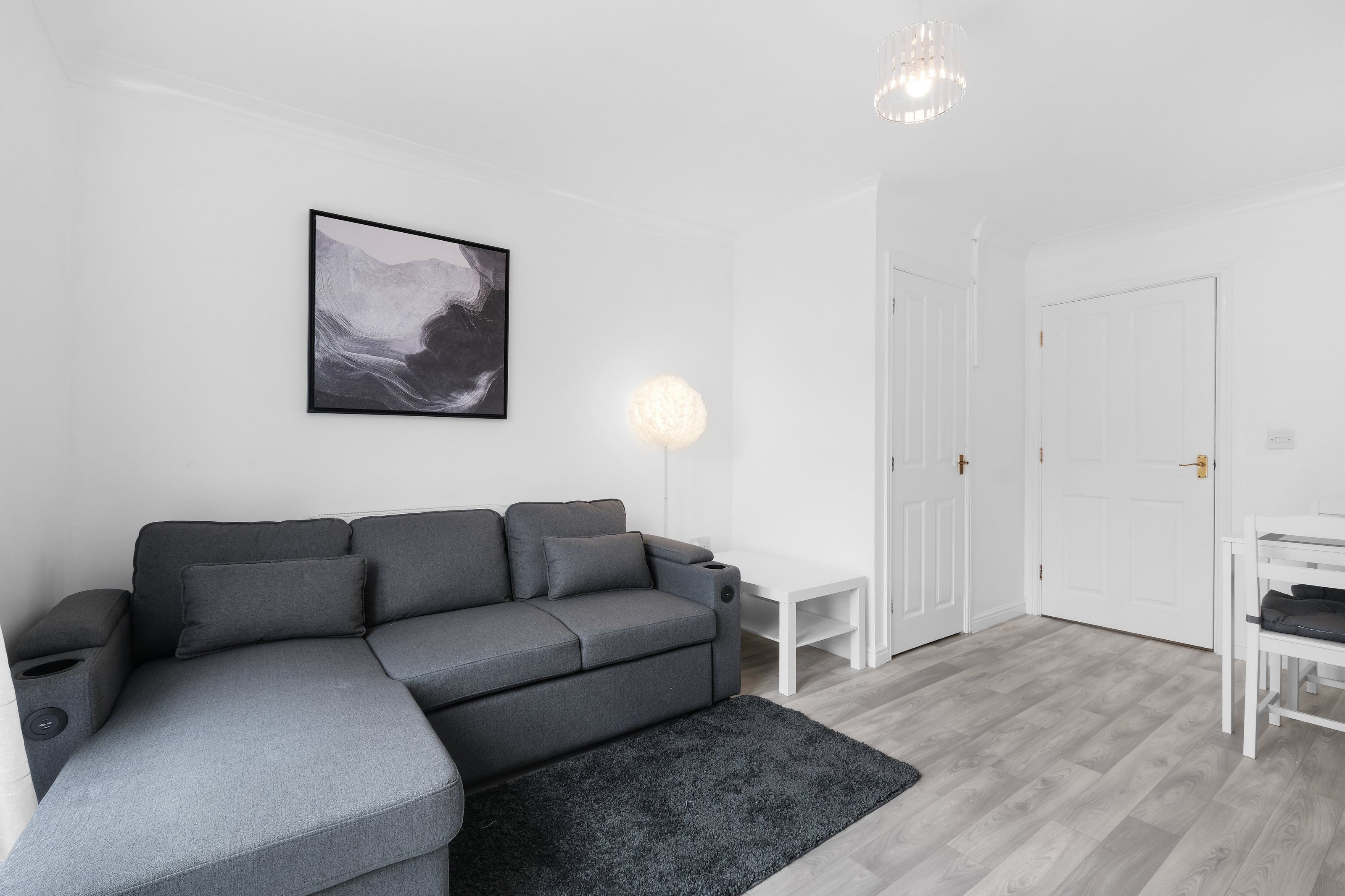 A modern living room with a grey sectional sofa, a round table, and a white door.