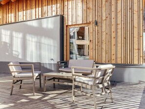 An outdoor seating area with a table and chairs, wooden panel walls, and a view of a building with a balcony. - Cabin in Niederwolz With Sauna (Oberwölz)
