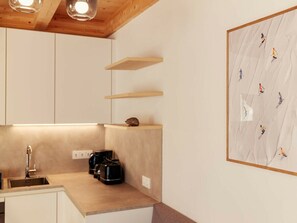 A modern kitchen with wooden cabinets, a built-in coffee maker, and a wall-mounted shelf. - Cabin in Niederwolz With Sauna (Oberwölz)