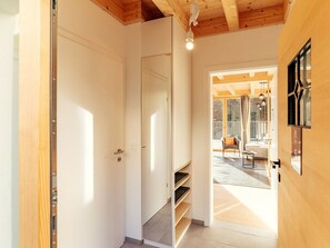 A hallway with a wooden ceiling, a white door, and a view into a room with a balcony. - Cabin in Niederwolz With Sauna (Oberwölz)