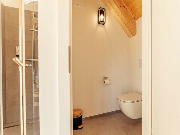 A bathroom with a shower, toilet, and a trash bin. - Cabin in Niederwolz With Sauna (Oberwölz)