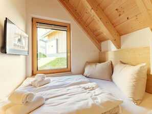 A bedroom with a wooden ceiling, a large window, and a bed with white linens and pillows. - Cabin in Niederwolz With Sauna (Oberwölz)