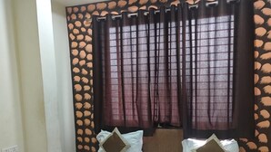 A bedroom with a bed, two pillows, a headboard, and a window with curtains. - Hotel The Stay Inn (Indore)