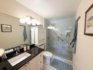 A modern bathroom with a glass-enclosed shower, a white toilet, and a black countertop sink. - Aventura Eden - 2-bedroom, Pool, Gym, Mall and Beach Oasis (Miami)