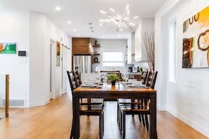 A modern dining area with a wooden table set for four, surrounded by chairs. - Central Edmonton Home | Walk to 124St Restaurants | 5min downtown | Pet Friendly (Edmonton)
