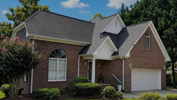 A two-story house with a brick facade, a front porch, and a garage. - Serene 4-bedroom house near Elon (Burlington)