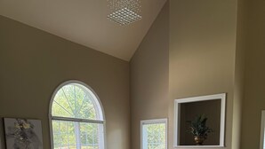 A spacious living room with a fireplace, large windows, and a blue sofa. - Serene 4-bedroom house near Elon (Burlington)