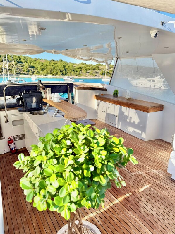 A boat deck with a coffee maker, a small table, and a potted plant.