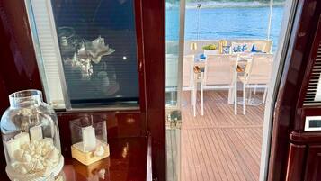A view from a ship's cabin to an outdoor deck with a table and chairs.
