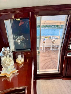 A view from a ship's cabin to an outdoor deck with a table and chairs.