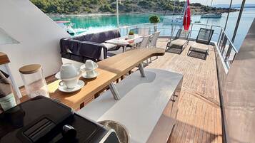 A sunlit deck with a table, chairs, and a grill.