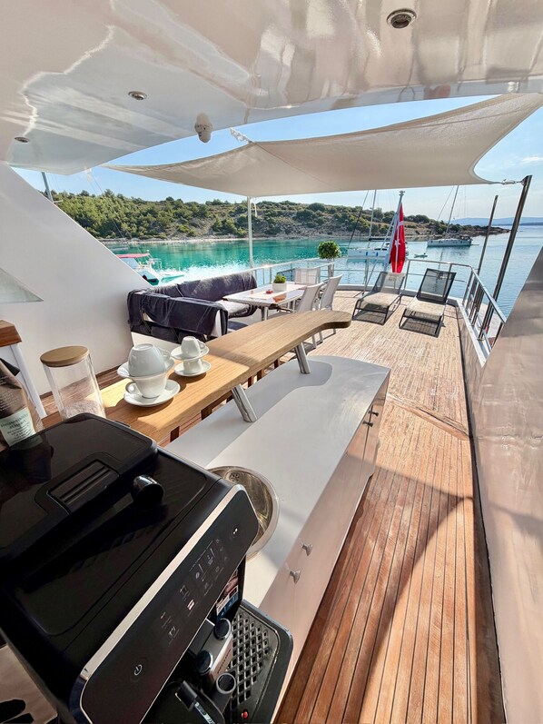Une terrasse ensoleillée avec une table, des chaises et un barbecue.
