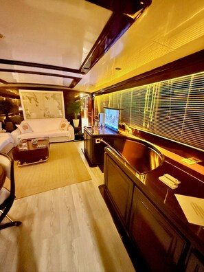 Un intérieur moderne comprenant un canapé, une table basse, un téléviseur et un coin cuisine avec un évier et une cuisinière.