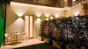 Ein zweistöckiges Gebäude mit Balkon, Sitzgelegenheiten im Freien und einer Zierwand.