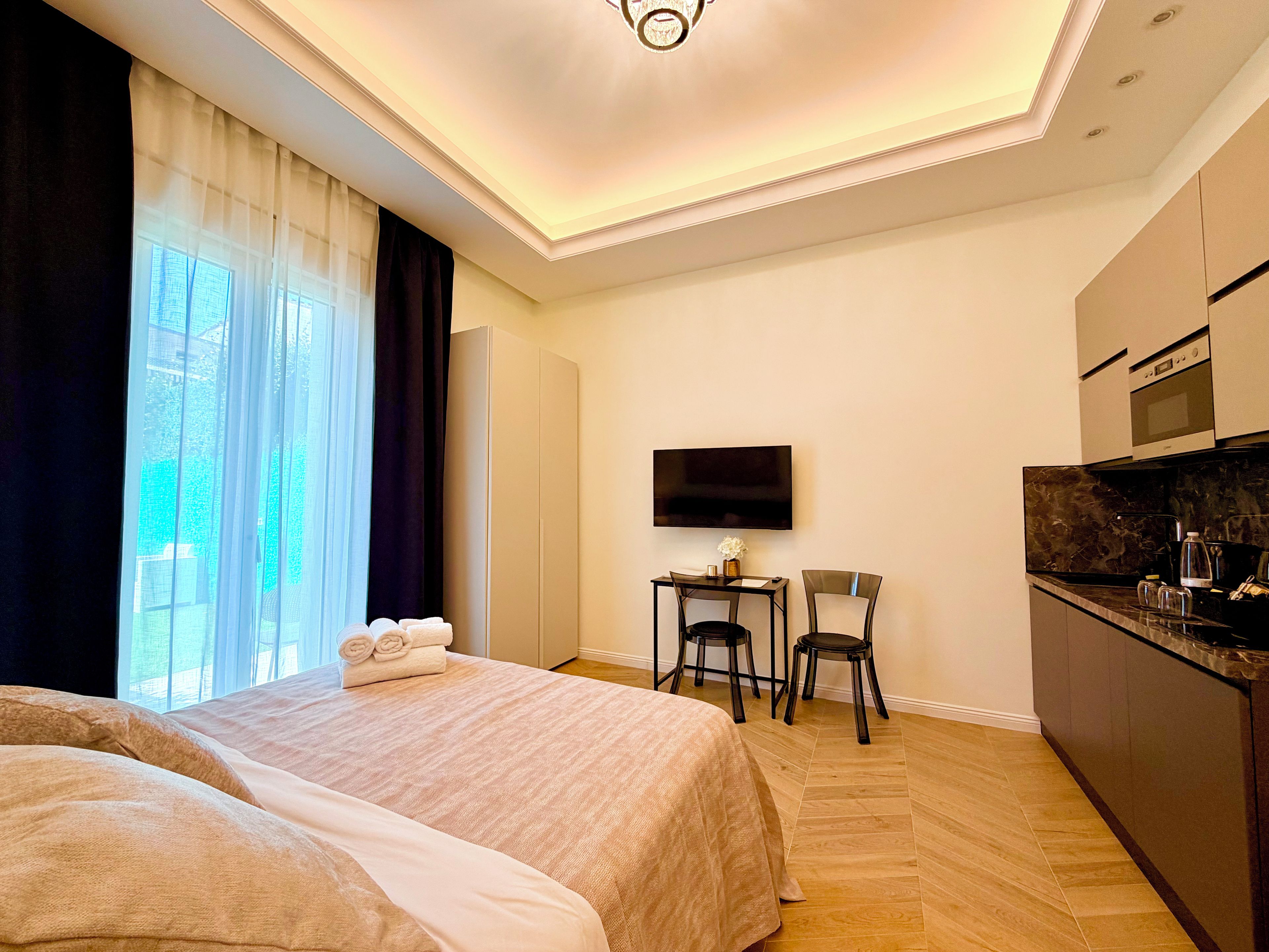 Una camera d'albergo con un letto, una scrivania con sedie, una televisione e angolo cottura.