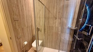 Ein modernes Badezimmer mit einer gläsernen Duschkabine, einer Toilette und einem Waschtisch mit Spiegel.