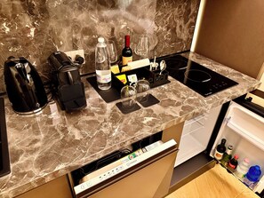 Cocina moderna con encimera de mármol, cafetera, una botella de vino y una cocina vitrocerámica empotrada.