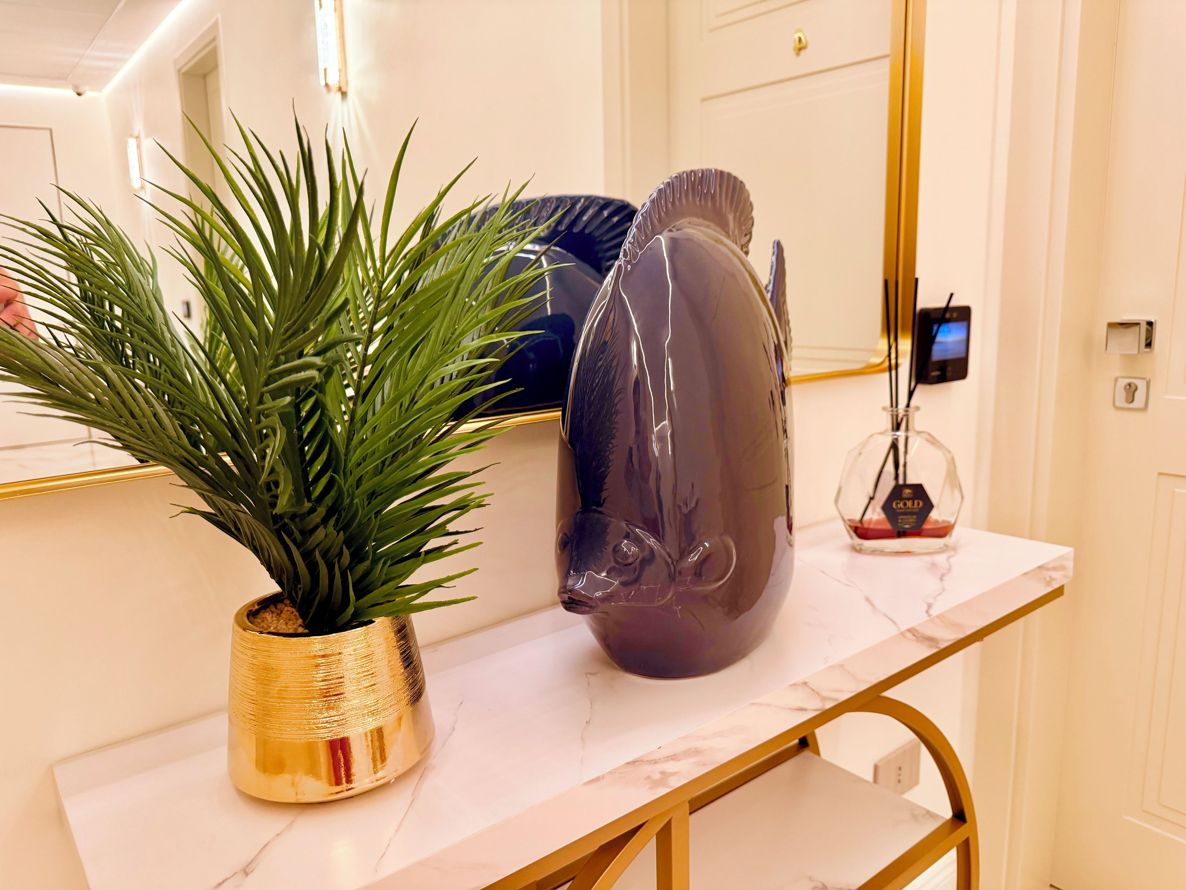 Un tavolo con piano in marmo, un vaso decorativo e una pianta in vaso.