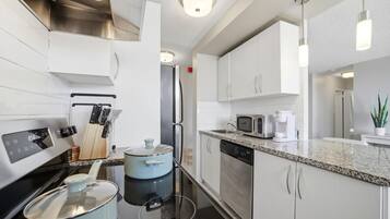 A modern kitchen with white cabinetry, stainless steel appliances, and a granite countertop.