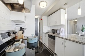 A modern kitchen with white cabinetry, stainless steel appliances, and a granite countertop.