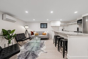 A modern kitchen with white cabinets, a stainless steel refrigerator, and a black countertop. - Cozy 2BR Basement Suite in Leslieville (Toronto)