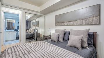 A bedroom with a bed, a nightstand, a mirror, and a large abstract painting on the wall.
