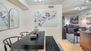Un espace repas moderne avec une table en bois foncé, des chaises noires et une œuvre d’art en marbre accrochée au mur.
