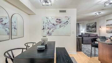 A modern dining area with a dark wooden table, black chairs, and a marble artwork on the wall.