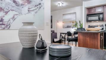 A modern kitchen with a marble backsplash, a dining area with a dark wooden table, and a bar area with a microwave.