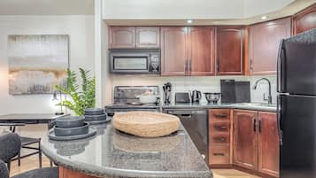 A modern kitchen with wooden cabinets, a microwave, a stove, and a refrigerator.