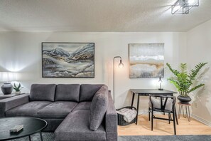 A modern living room with a grey sofa, a round coffee table, a dining table with chairs, and two paintings on the wall. - Downtown 1BR Condo w/ WFH Setup & Private Balcony (Toronto)