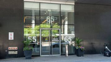 A private residence entrance with glass doors, numbered 55 and 65, and a sign indicating no smoking and no vaping.