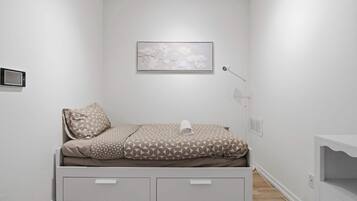 A minimalist bedroom with a bed, a wall-mounted artwork, a bedside lamp, and a small storage unit.