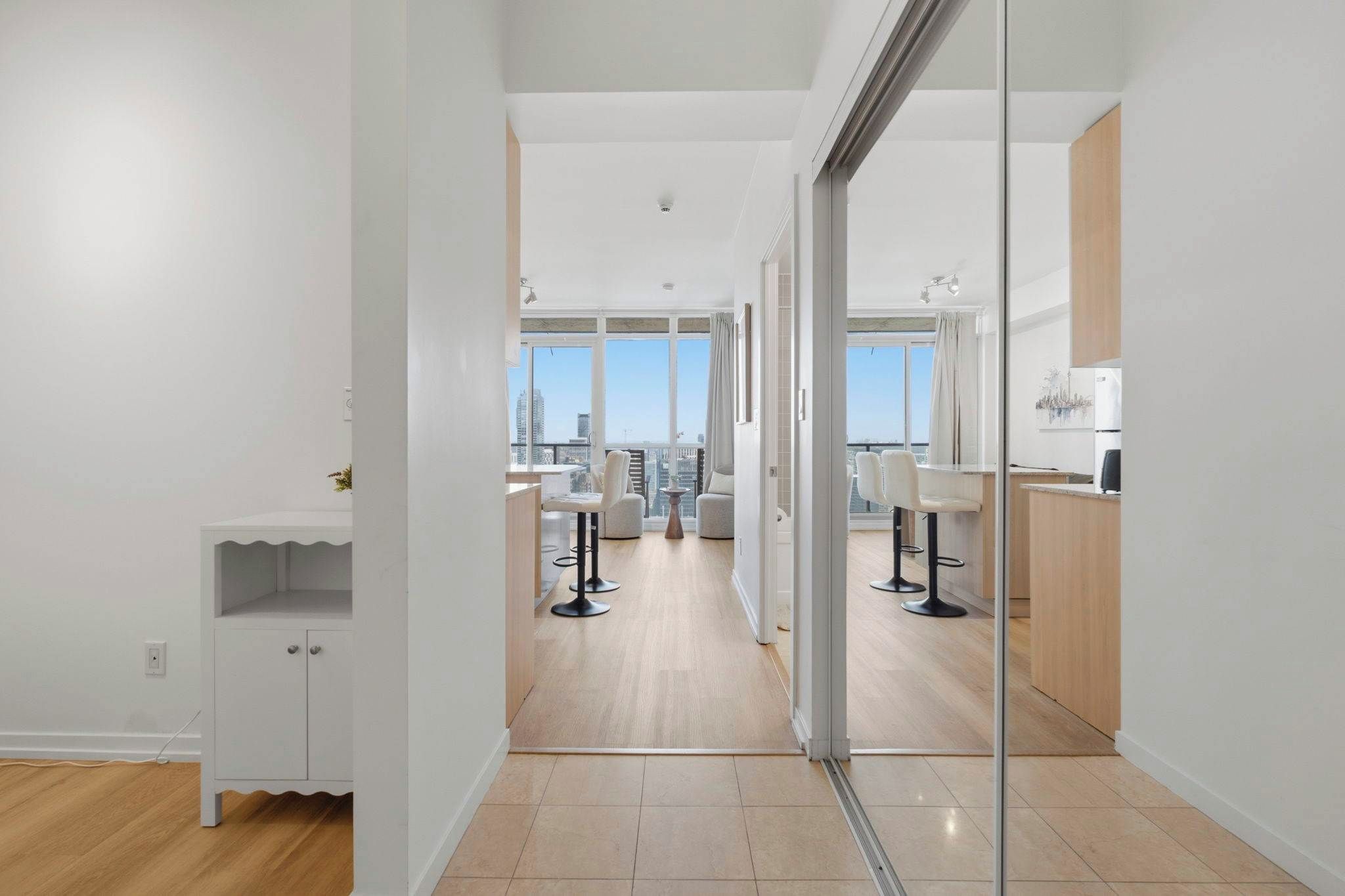 Ein modernes Interieur mit einem Flur, der in einen Essbereich mit hohen Decken und großen Fenstern mündet.