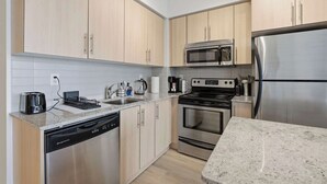 Uma cozinha moderna com eletrodomésticos de aço inoxidável, armários de madeira clara e bancada de granito.