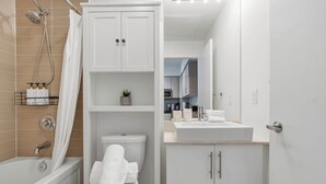 A modern bathroom with a bathtub, toilet, and a sink area. - CN Tower View Condo - Balcony, WiFi & Workspace (Toronto)