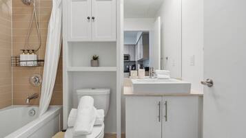 A modern bathroom with a bathtub, toilet, and a sink area.