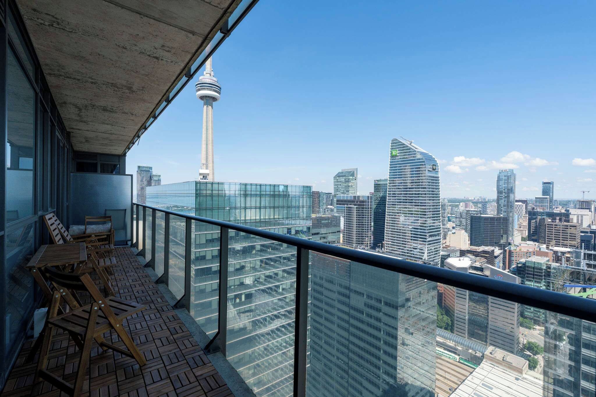 A balcony with a city view, including a tower and modern buildings.