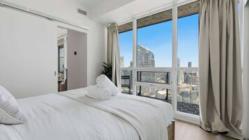 A hotel room with a large window, a bed, and a city view.