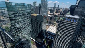 A high-rise urban area with modern glass buildings, including a prominent one with a curved facade and a visible logo. - CN Tower View Condo - Balcony, WiFi & Workspace (Toronto)