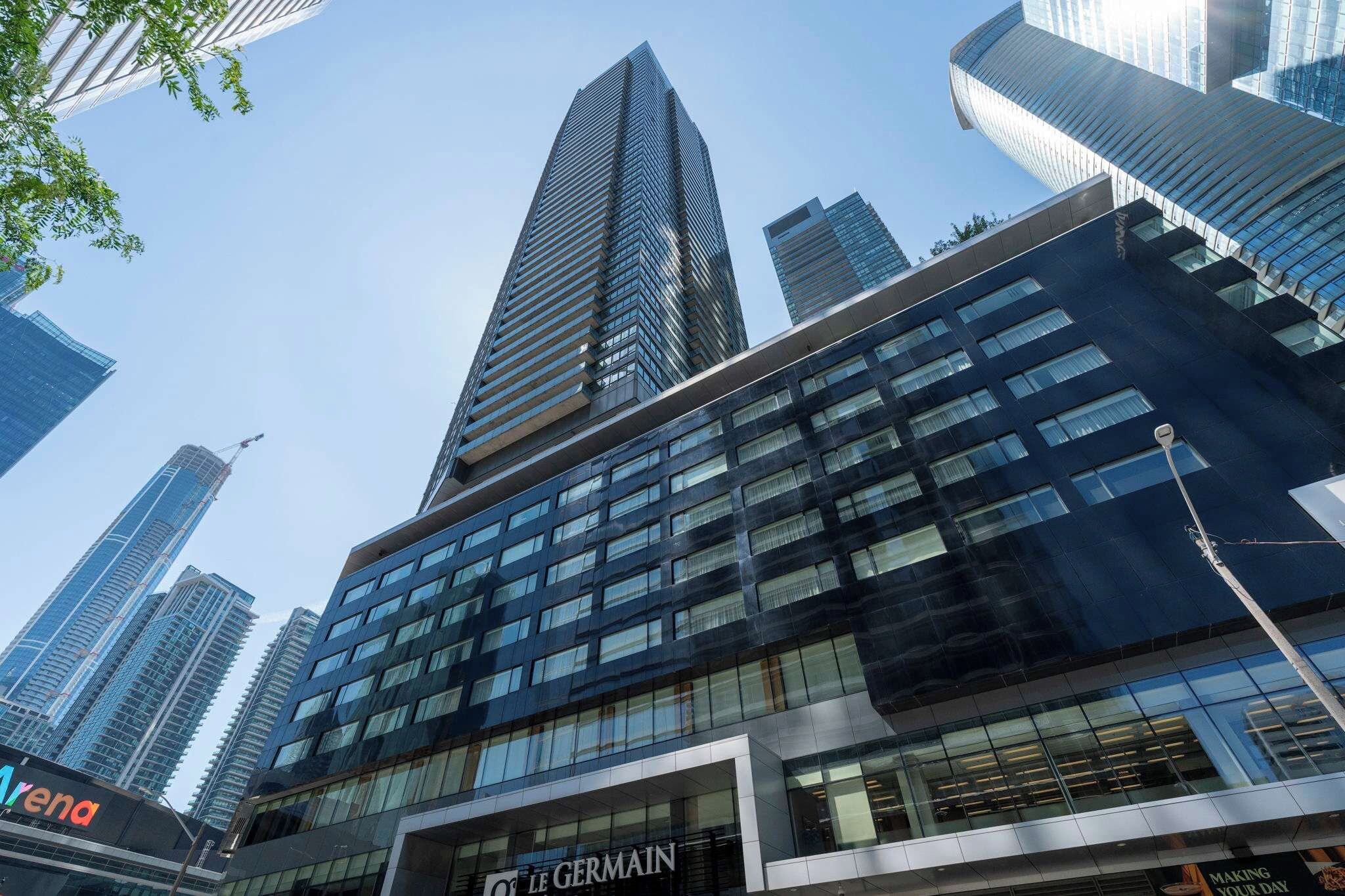 A modern building with a prominent glass facade, multiple floors, and a clear sky in the background.