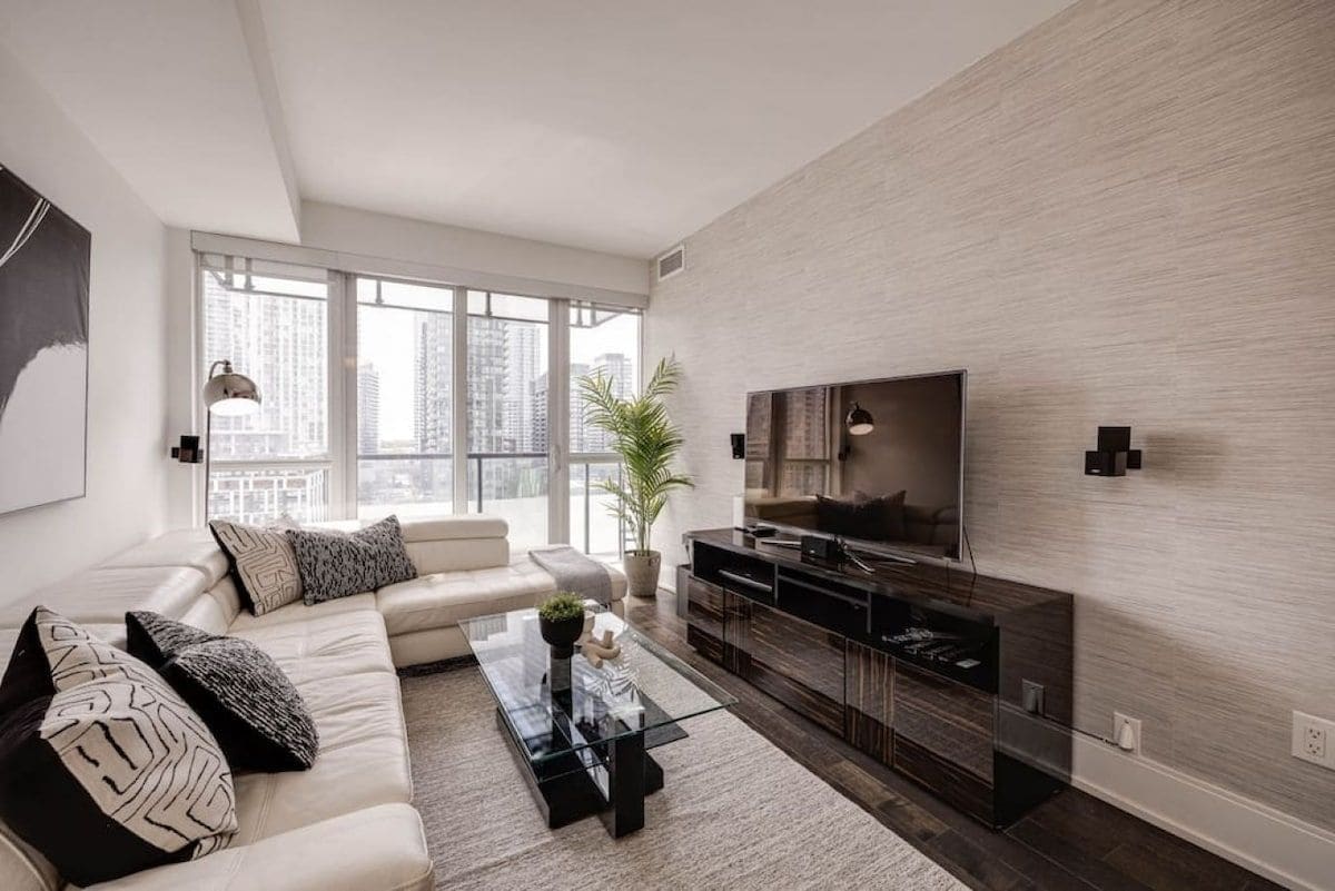 A modern living room with a sofa, coffee table, TV, and a city view.