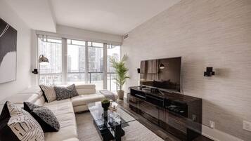 A modern living room with a sofa, coffee table, TV, and a city view.