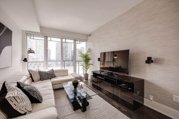 A modern living room with a sofa, coffee table, TV, and a city view.