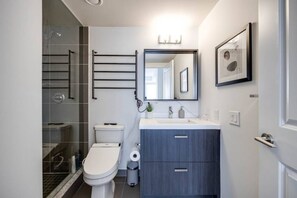 A modern bathroom with a toilet, sink, and shower area.