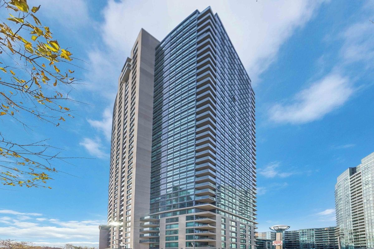 A high-rise building with a modern architectural design, featuring a prominent glass facade and a series of balconies.
